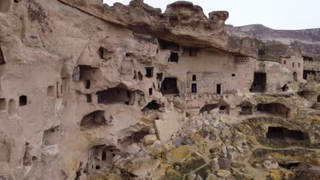 A-woman-standing-on-Ancient-stone-dwellings-carved-from-tuff-in-Cappadocia-Turkey