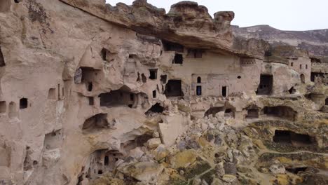 a woman standing on ancient stone dwellings carved from tuff in cappadocia turkey