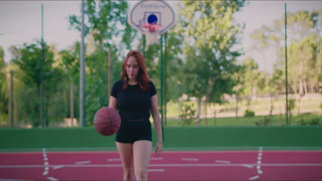 basketball court redhead girl holds ball and faces the camera slow motion