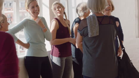 yoga class of happy old women chatting enjoying healthy fitness lifestyle sharing conversation in wellness workout studio