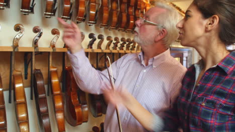 salesman advising customer buying violin