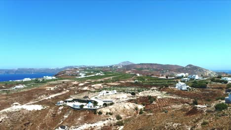 Aerial-4K-Blue-Sea-and-Sky-Top-View-While-Rising-of-Village-of-Akra-Mavro-Vouno-in-Santorini-Greece