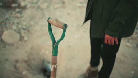 close up of man taking a shovel to dig in a hostile and arid environment