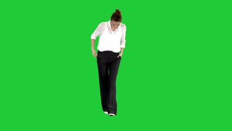 walking businesswoman with hands in pockets and laughing on a green screen, chroma key