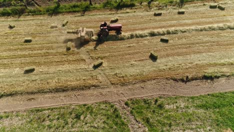 Haystacks-on-the-field-and-tractor-working-on-the-natural-green-background