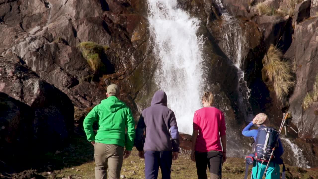 excursionistas caminando en cámara lenta hacia la cascada.mp4