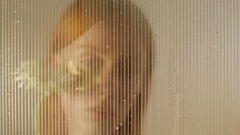 woman with flower face mask behind a wet glass