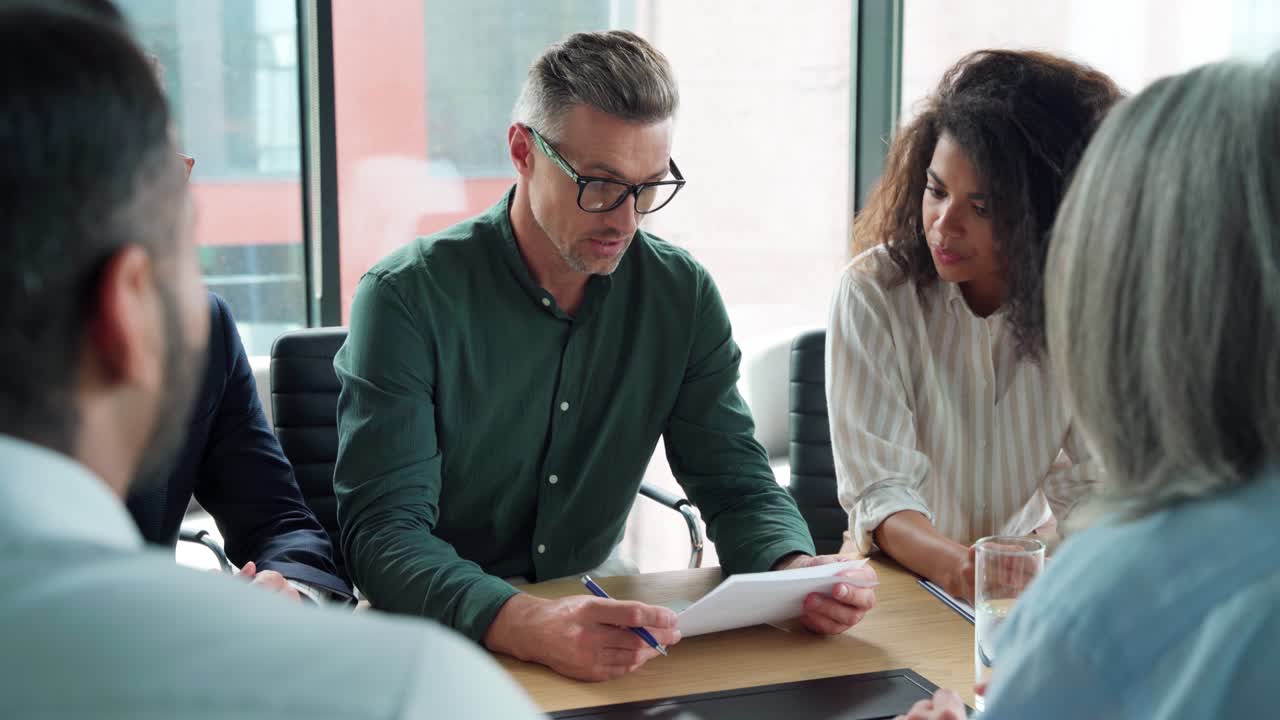 un hombre de negocios firmando un contrato en una reunión de grupo estrechando la mano de un socio de negocios.