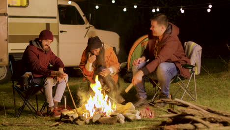 bearded man telling a funny joke to his friends around camp fire