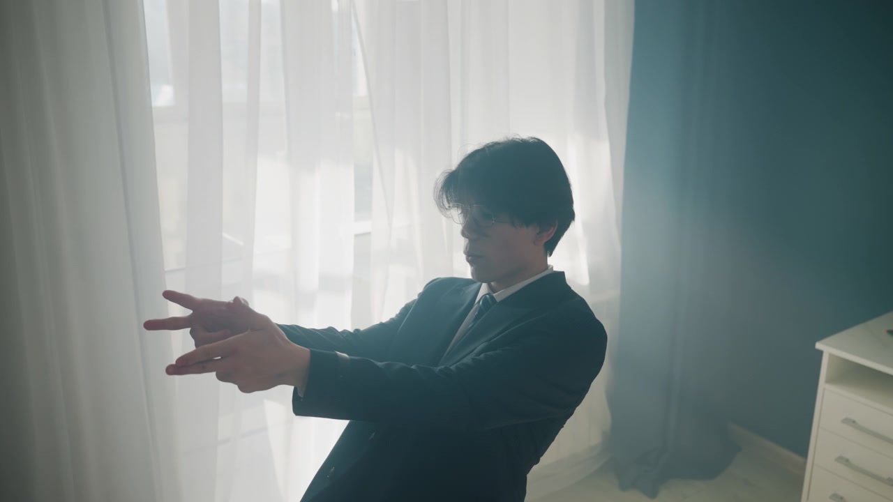 明るいオフィスで窓際でジェスチャーを練習する白人男性。行ったり来たりしながらプレゼンテーションを模倣し、神経質にそわそわしながら袖とネクタイを確認する。ドラマチックなシルエットと緊張感のあるシネマティックな照明の中、一時停止して呼吸を整える。