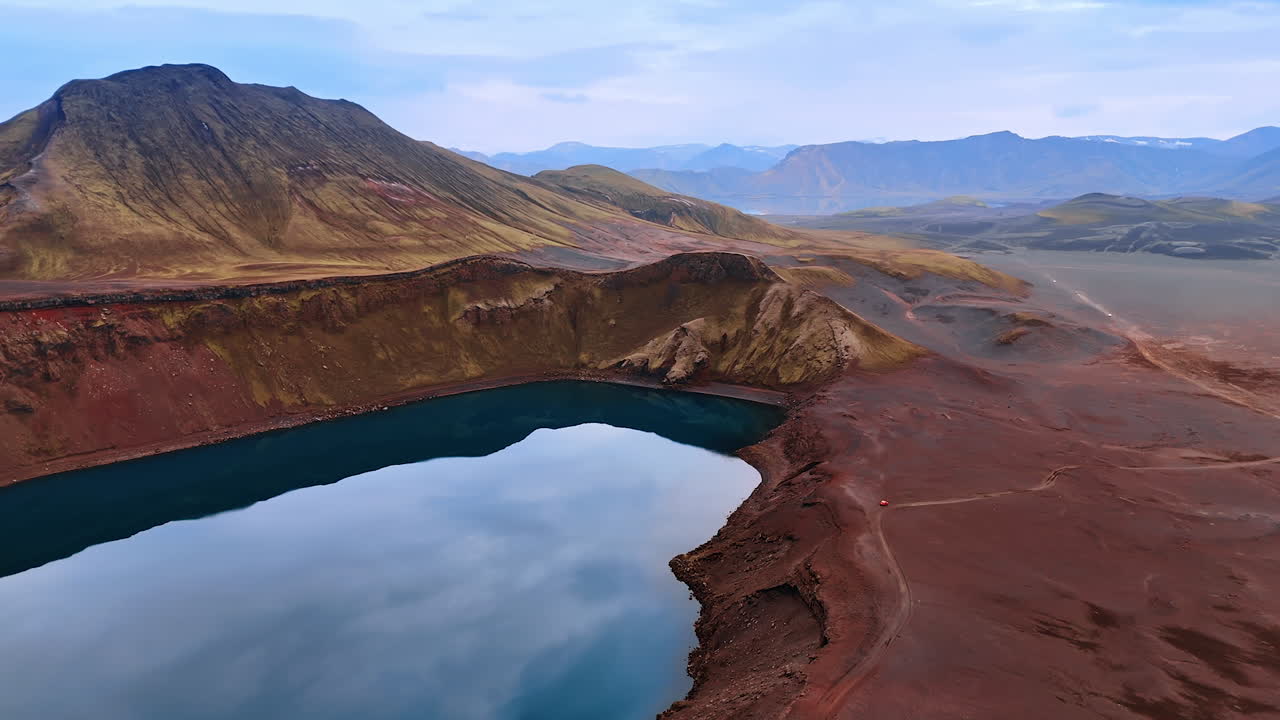 Water filling the crater of sleeping volcano. Bare mountainous landscape with no vegetation. Iceland scenery from top view.