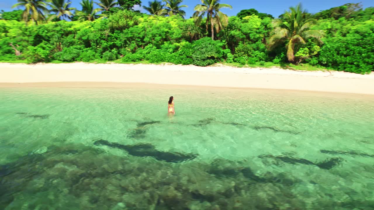 Happy female walking through turquoise water on tropical island beachfront, Yasawa, Fiji