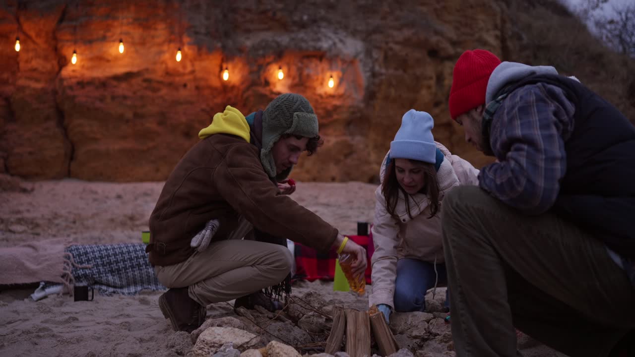 Friends Camping by a Bonfire at the Beach at Sunset