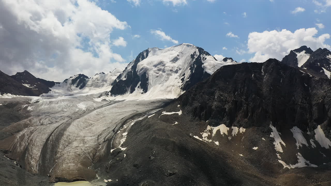 toma aérea giratoria de una montaña y un glaciar sobre el lago ala-kol en kirguistán