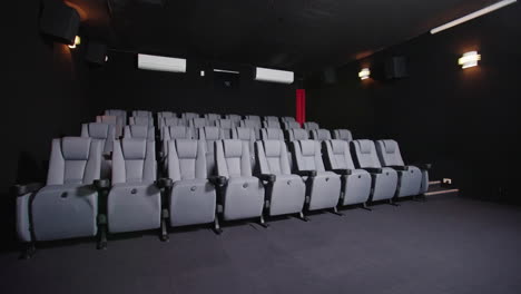 filas de asientos frente a la pantalla en un pequeño cine local poco iluminado, 4k