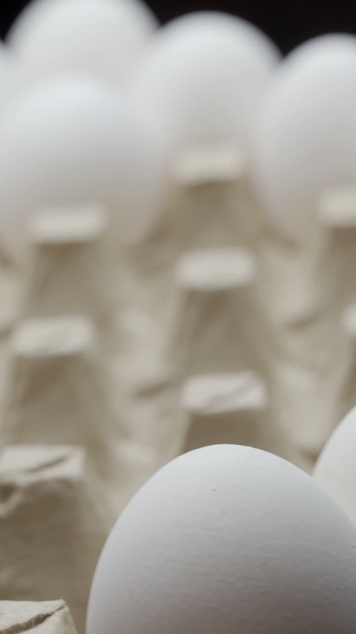 Close view of a farmer taking eggs from a pile and placing them into a carton to be sold Vertical video