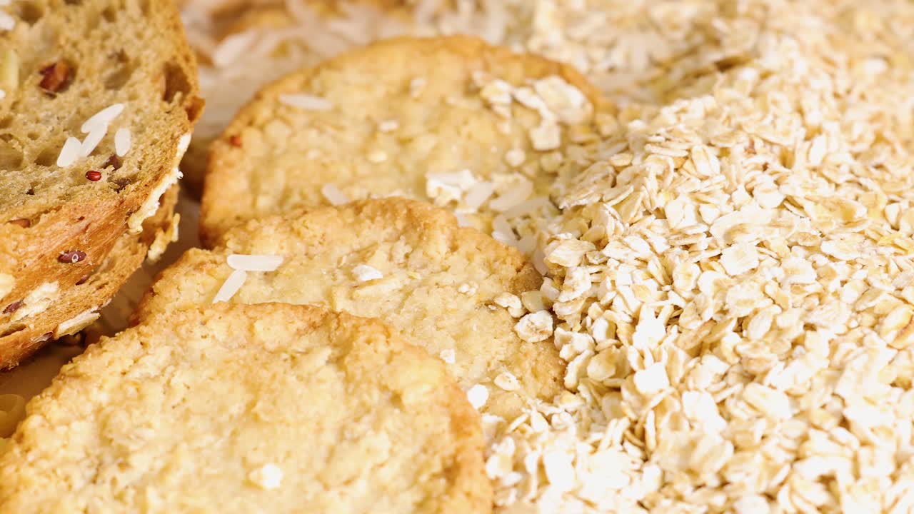 A close-up view of whole wheat bread, pasta, corn, and oats under warm lighting, highlighting texture and variety