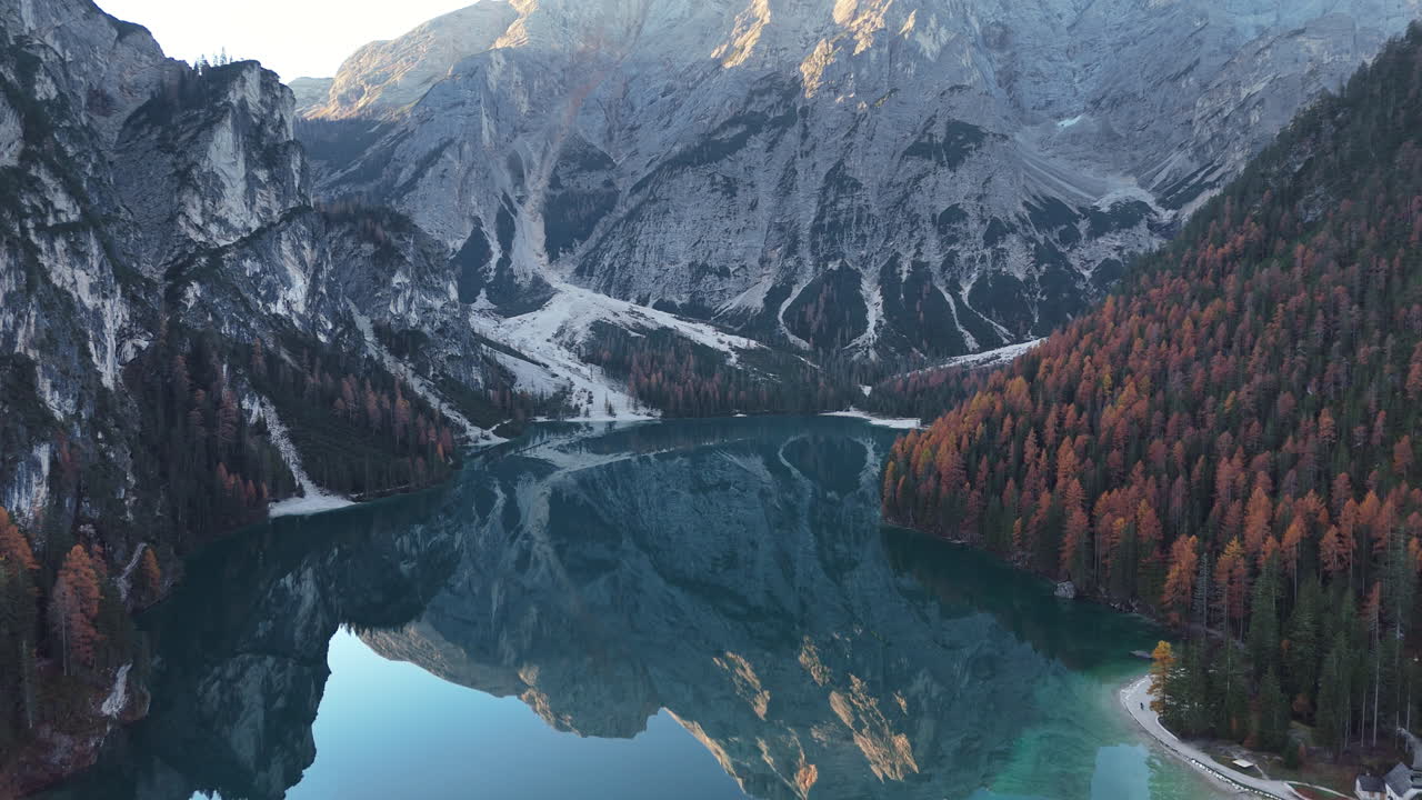 Mountain lake with colorful autumn trees and dramatic cliffs reflected in calm blue water