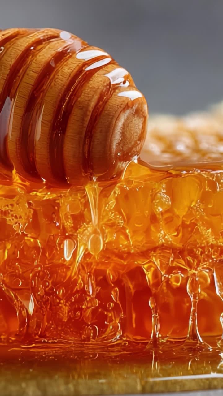 Un primo piano di miele dorato che cola da un mestolo di legno per miele su uno sfondo di favo magnifico, in un'atmosfera morbida e sognante