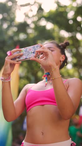 woman at a pride parade taking pictures with her smartphone