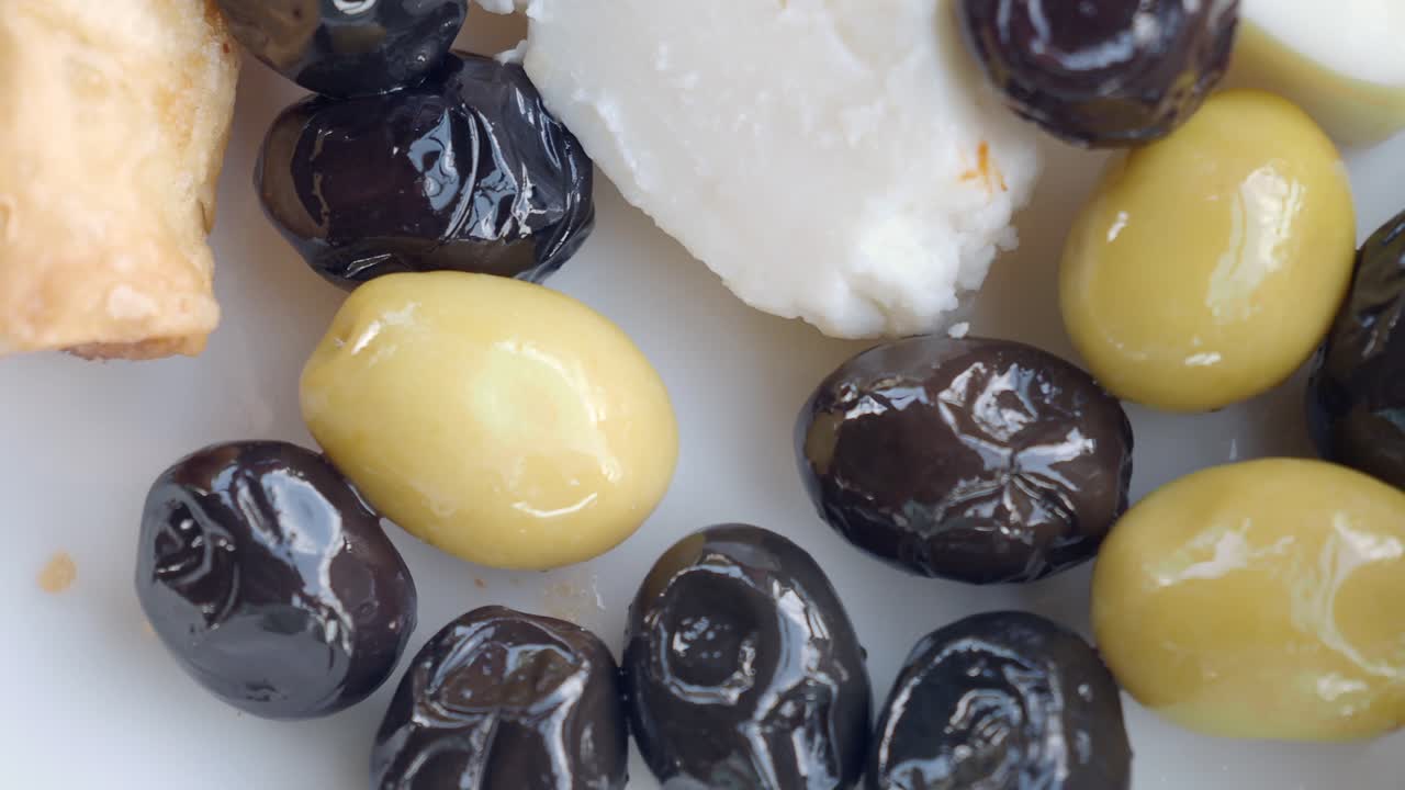 aceitunas verdes y negras con queso feta en un plato blanco