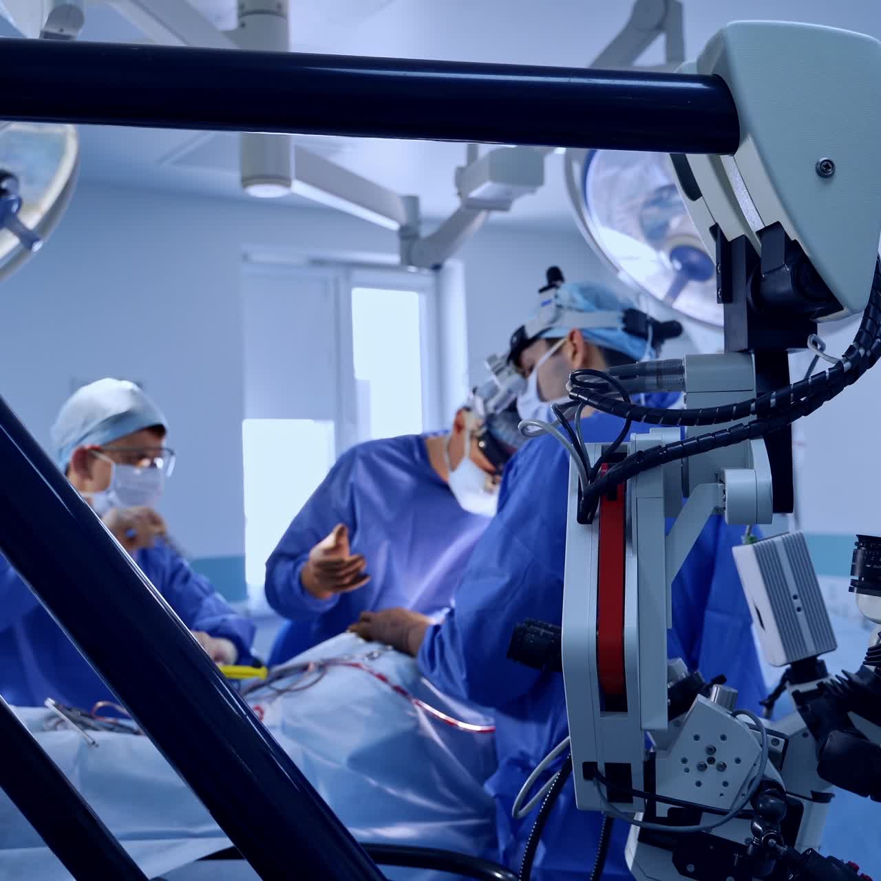 Big powerful technological microscope in modern surgery room. Doctor's team performing a surgery at backdrop