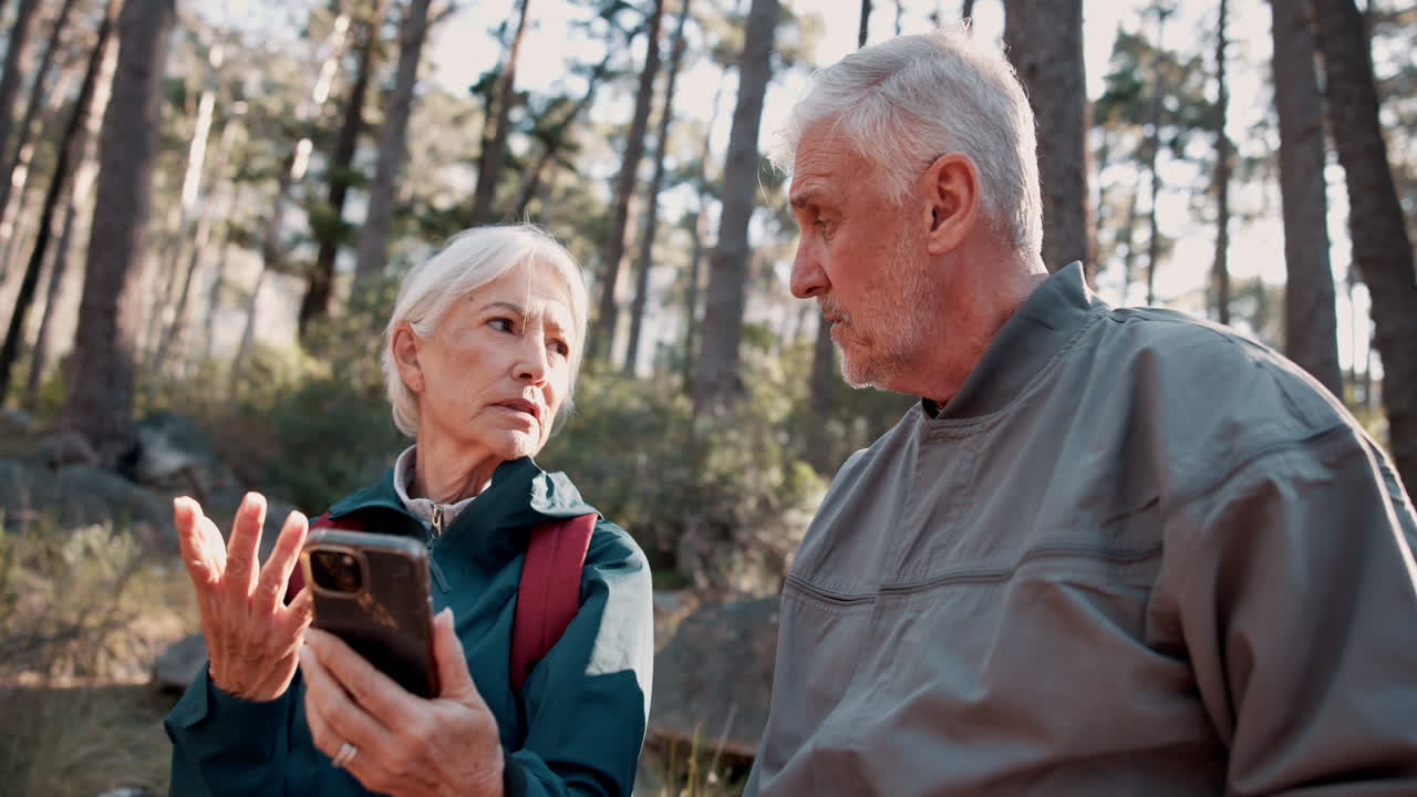 una pareja de ancianos usando un teléfono inteligente en el bosque.