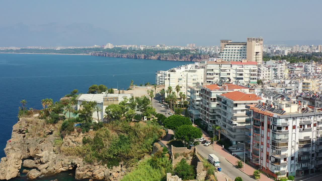 drones aéreos volando junto a grandes edificios de apartamentos residenciales en un soleado día de verano en antalya, turquía, con grandes acantilados rodeados por el mar mediterráneo