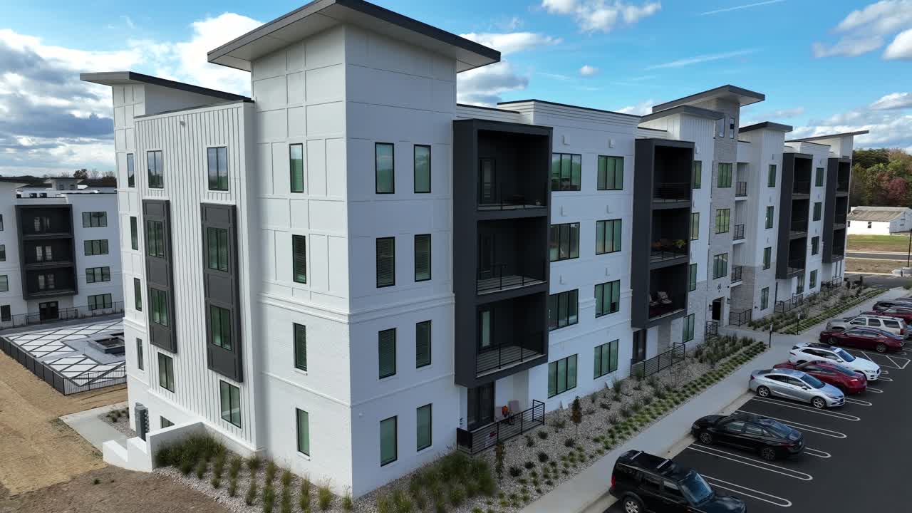 Modern design apartment buildings with parking cars with colored tree in suburb of USA. Aerial approaching shot. Massachusetts, America. Drone footage.