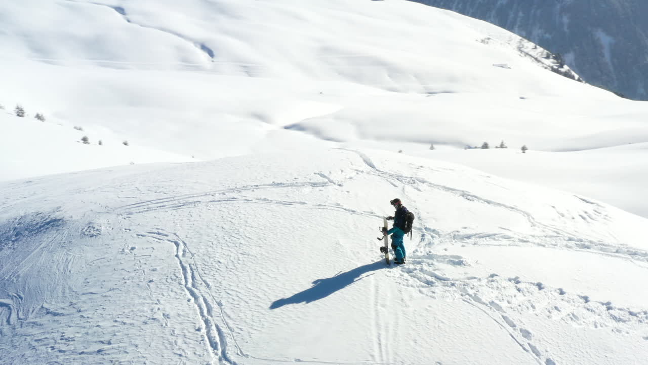 vista aérea, panorámica alrededor de un snowboarder parado en la cima de una montaña cubierta de nieve