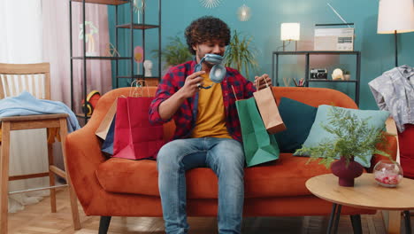 happy indian man shopaholic consumer came back home after online shopping sale with bags at home