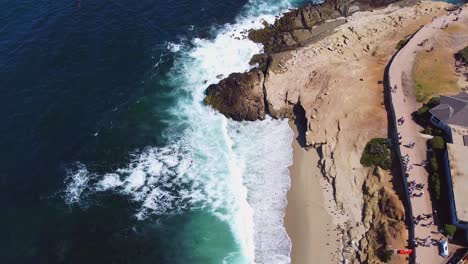 Vista-Aérea-De-La-Jolla-Mientras-La-Gente-Ve-Nadar-A-Los-Leones-Marinos-Y-Atrapar-Los-Rayos-Del-Sol-En-Las-Rocas