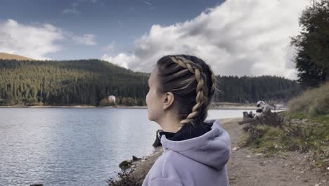 a woman mesmerized by the tranquil view of bolboci lake in bucegi mountains, romania