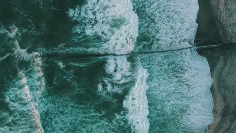 Aerial-cenital-plane-shot-of-waves-crashing-at-the-wall-of-Tijuana-Beach-at-sunset