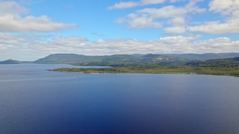 ascending flyover of huillinco lake on a sunny day, chonchi, chiloé island, chile