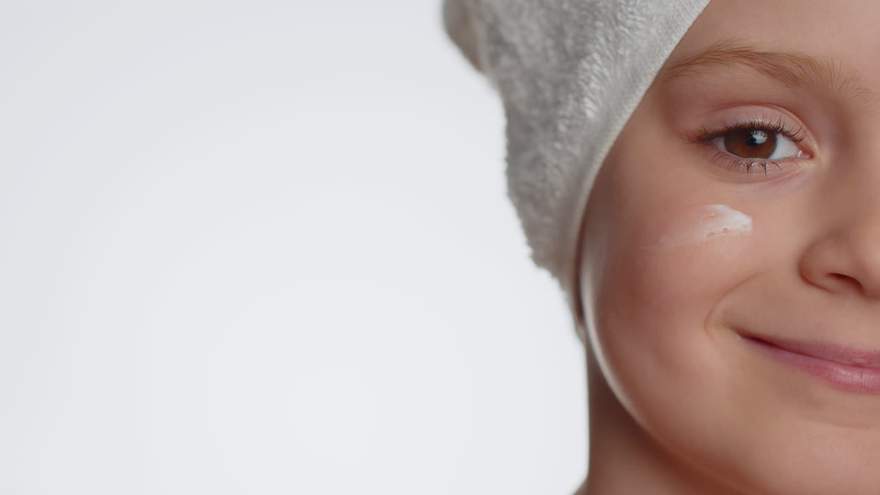 Sød ung pige påfører rensende, fugtgivende ansigtscreme; hudpleje, naturlig creme, kosmetik.