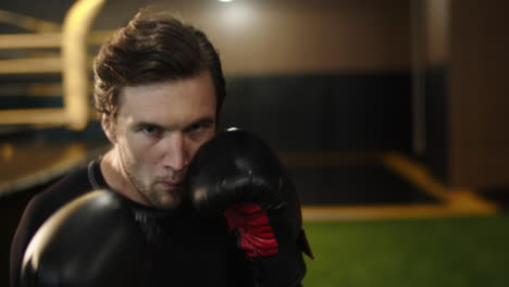 eager male athlete making blows in sport club. boxer training kicks at gym