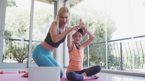 mother teaching yoga to her daughter at home