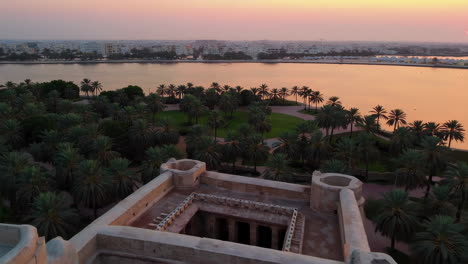 aerial view of a historical fort at sunset/sunrise over a lake and palm trees park