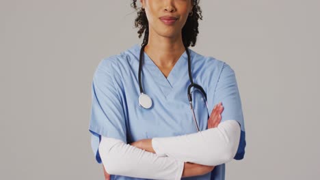 video de una doctora biracial sonriente con los brazos cruzados sobre un fondo azul