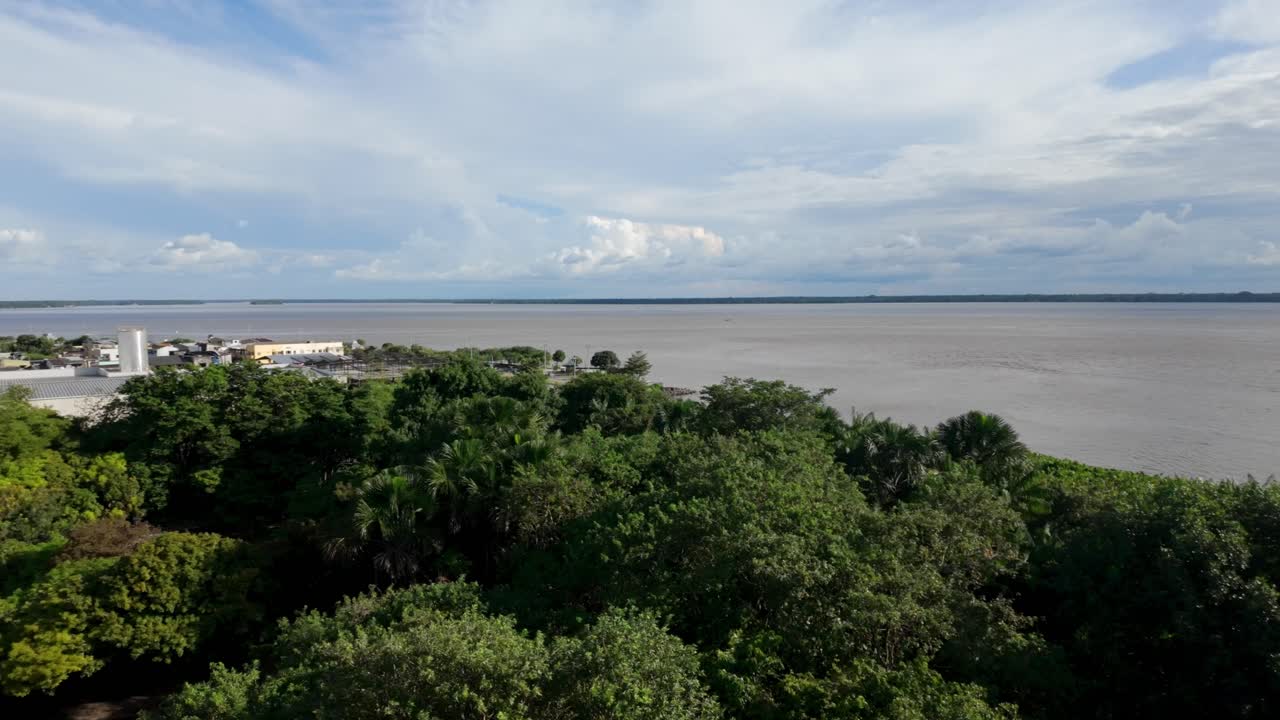 Expansive views of a wide river and lush Amazonian jungle under cloudy skies, with sun glare on the water and occasional distant boats or structures.