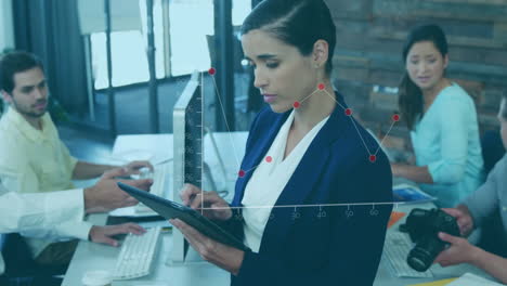 un ejecutivo de negocios usando una tableta digital mientras su colega trabaja en un escritorio en la oficina