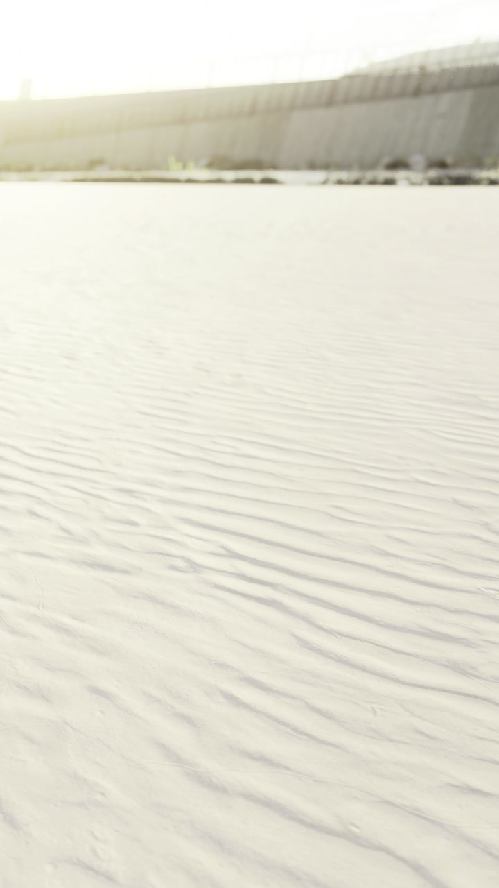 Rippling patterns of sand under the golden sun at a serene beach