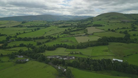 rising high above rolling green fields and hills of summer countryside on overcast day