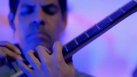 close up shot of guitarist's man face plying guitar instrument