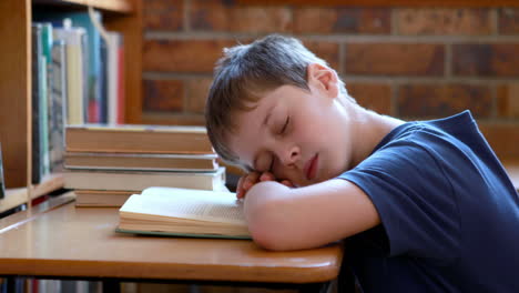 little boy sleeping on a book in classroom