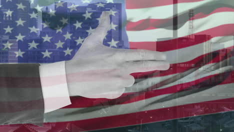 animation of hand of smart caucasian making gun gesture over waving american flag and city buildings