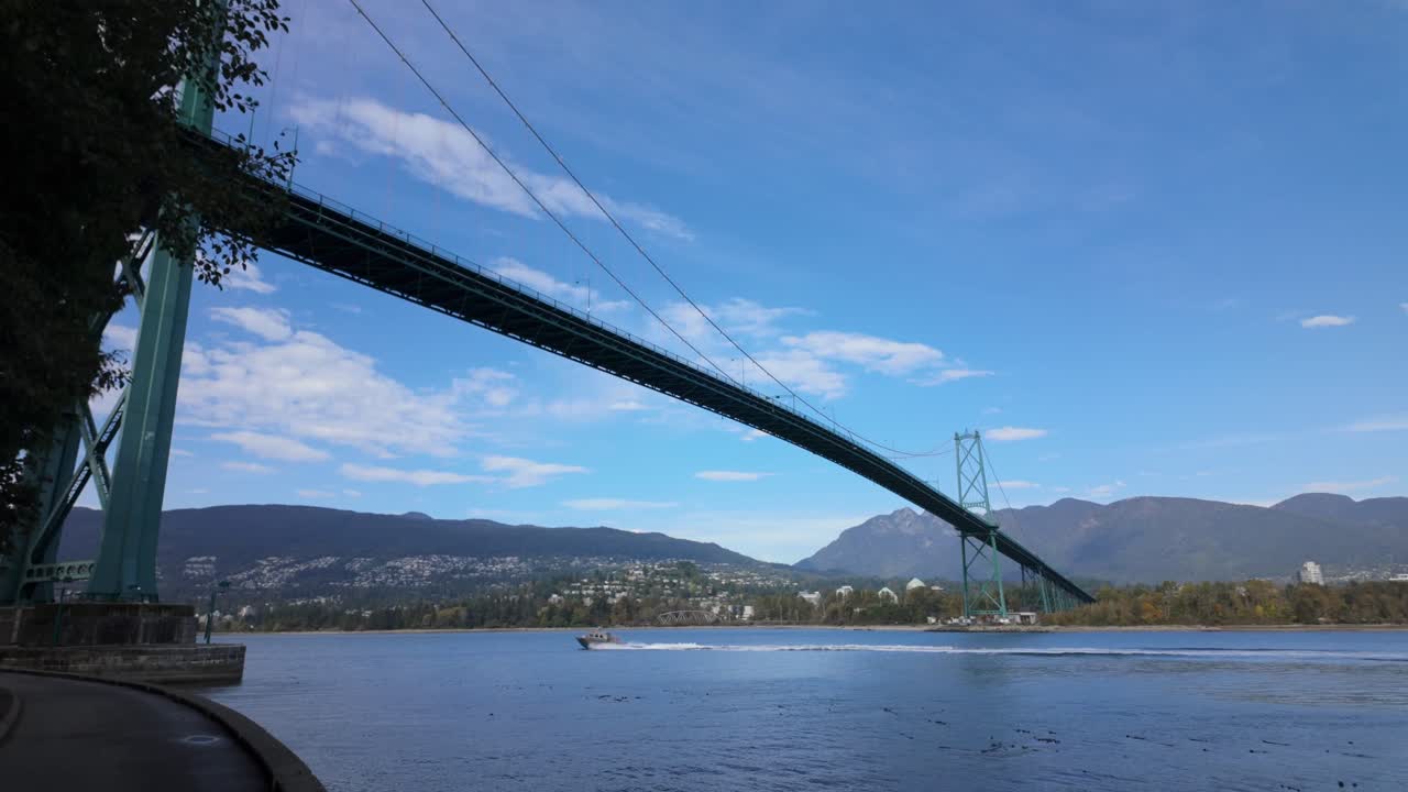 Gimbal wide panning shot of a boat traveling under Lions Gate Bridge in Vancouver, British Columbia, Canada. 4K