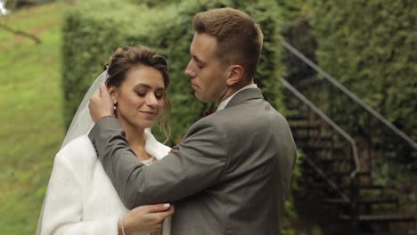 newlyweds, caucasian groom with bride walking, embracing, hugs in park, wedding couple