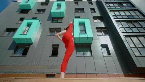 woman doing yoga or acrobatic poses outside a modern building.